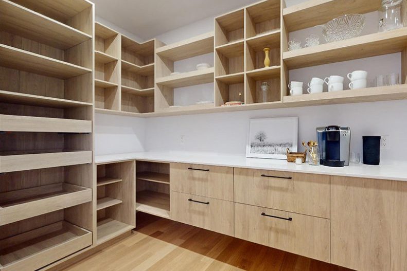 La cuisine de la maison modèle : îlot blanc, armoires marine et bois, tabourets noirs
