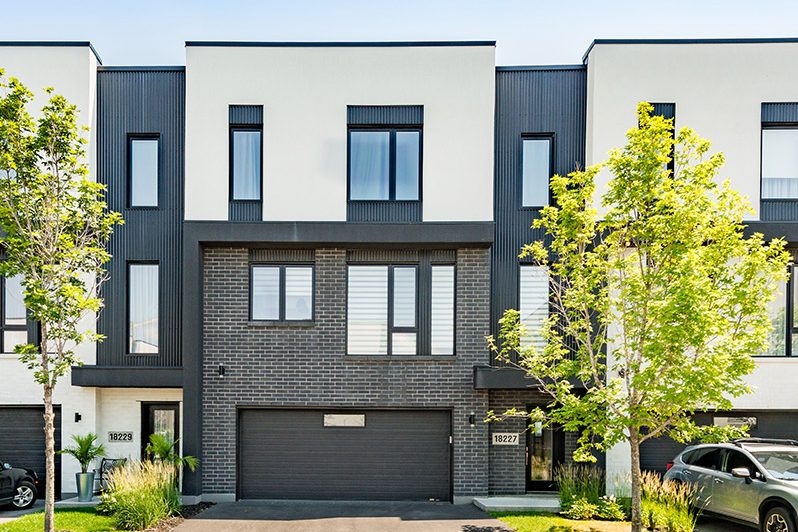 Villas Cité Mirabel : maisons de ville noires à garage, arbres en fleurs devant